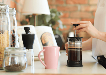 Man using French press surrounded by lots of useful accessories