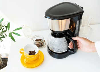 Barista holding the handle of glass carafe of coffee maker