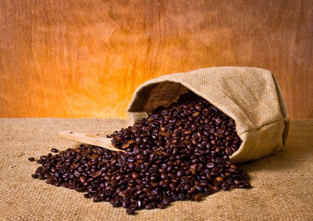 Whole roasted coffee beans placed in jute bag