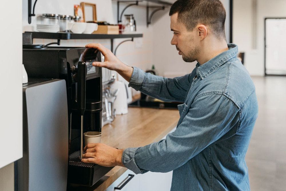 Businessman dispensing coffee from coffee urn during office break