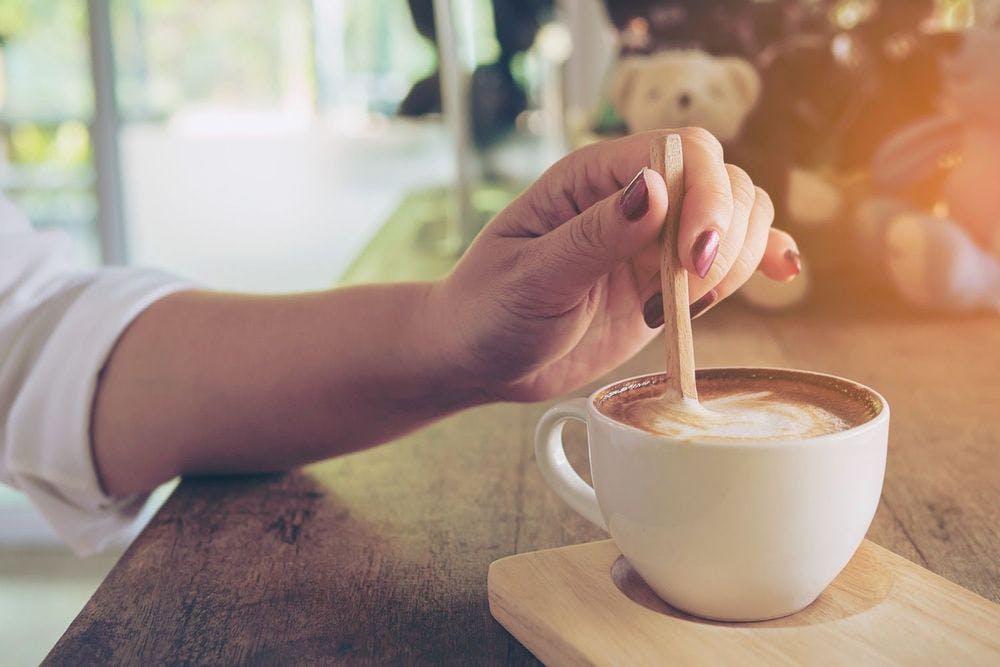 Lady stirring coffee with wooden stick