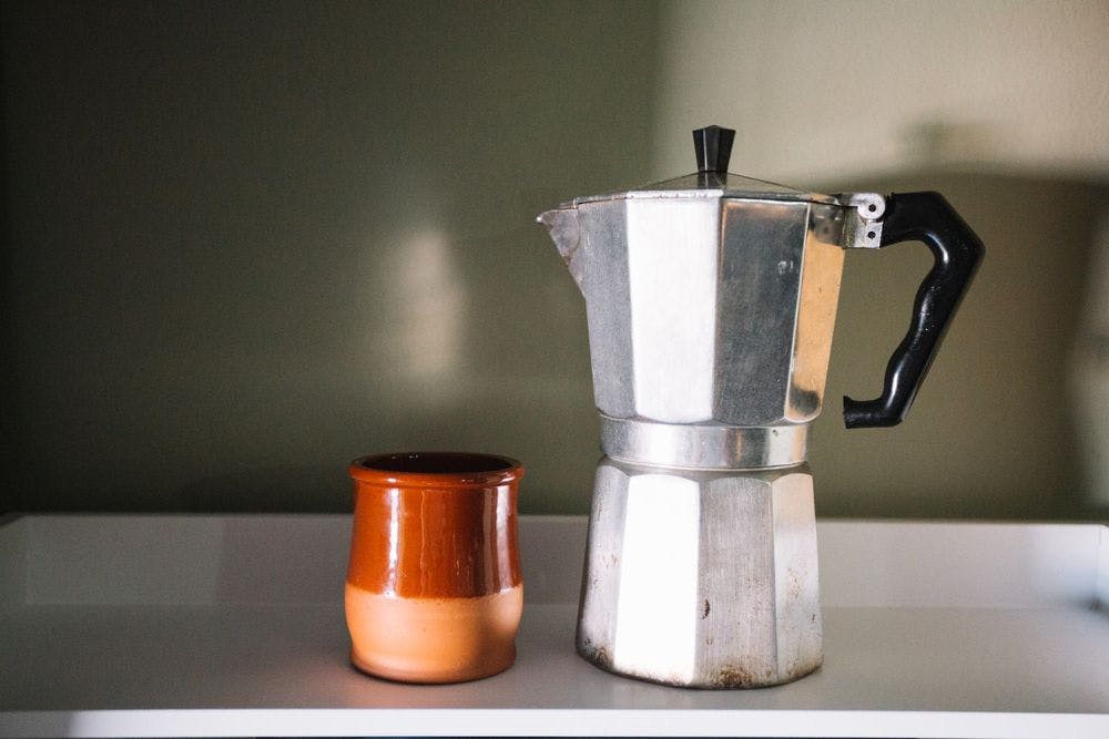 Cleaned moka pot is put beside a ceramic cup