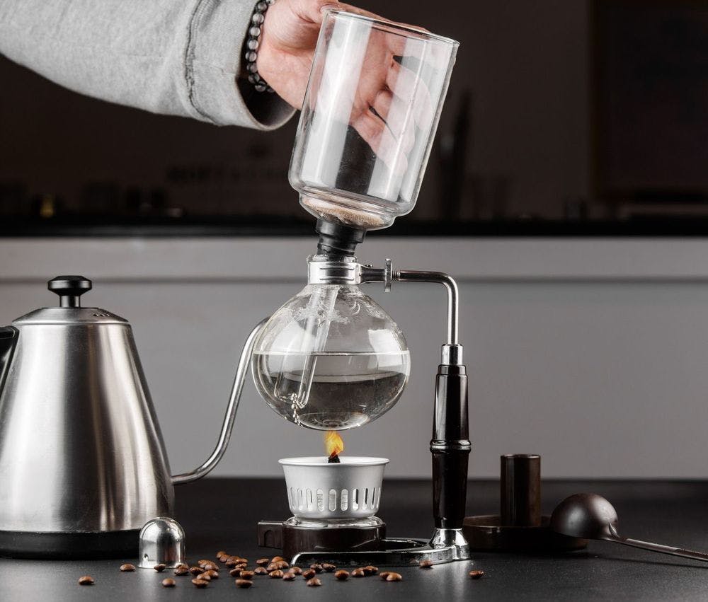 Barista brewing coffee using a syphon coffee maker