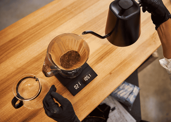 Barista pouring hot water on the brown coffee paper filter