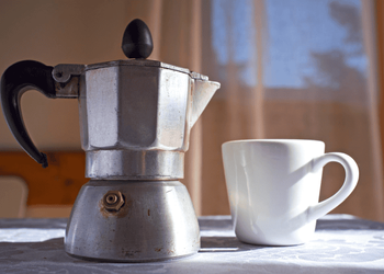 Moka pot is shown with white ceramic cup