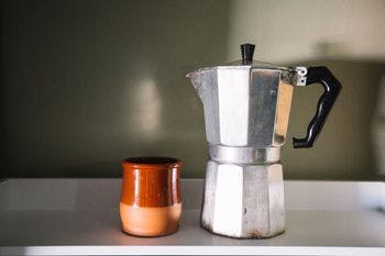 Cleaned moka pot is put beside a ceramic cup